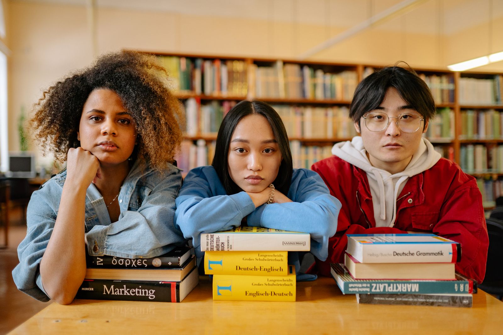 Un groupe d'étudiants divers engagés dans leurs études à la bibliothèque, entouré de livres et de ressources.